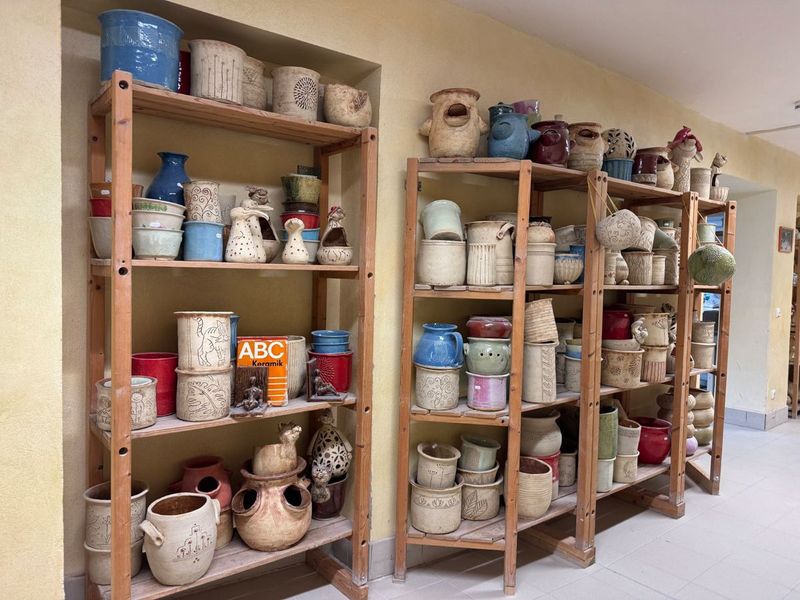 Bunte glasierte Becher, Krüge und Tierfiguren in Holzregalen